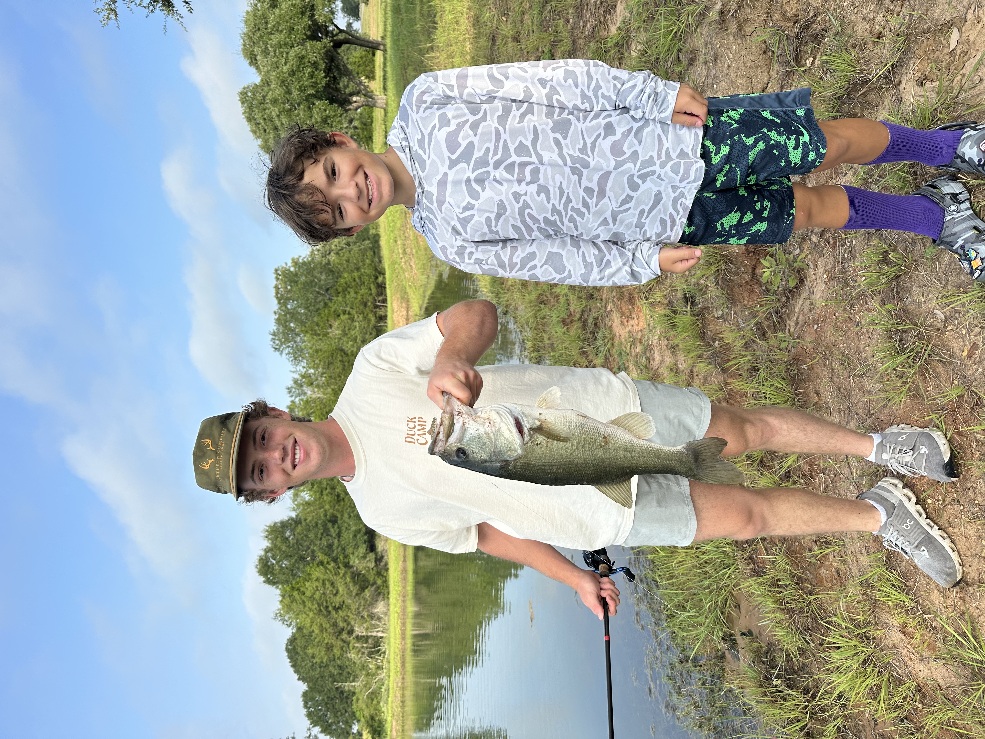 Angler holding a largemouth bass caught on a Chuck's Bass Candy handcrafted soft plastic lure — Brothers, one rod, one fat bass.