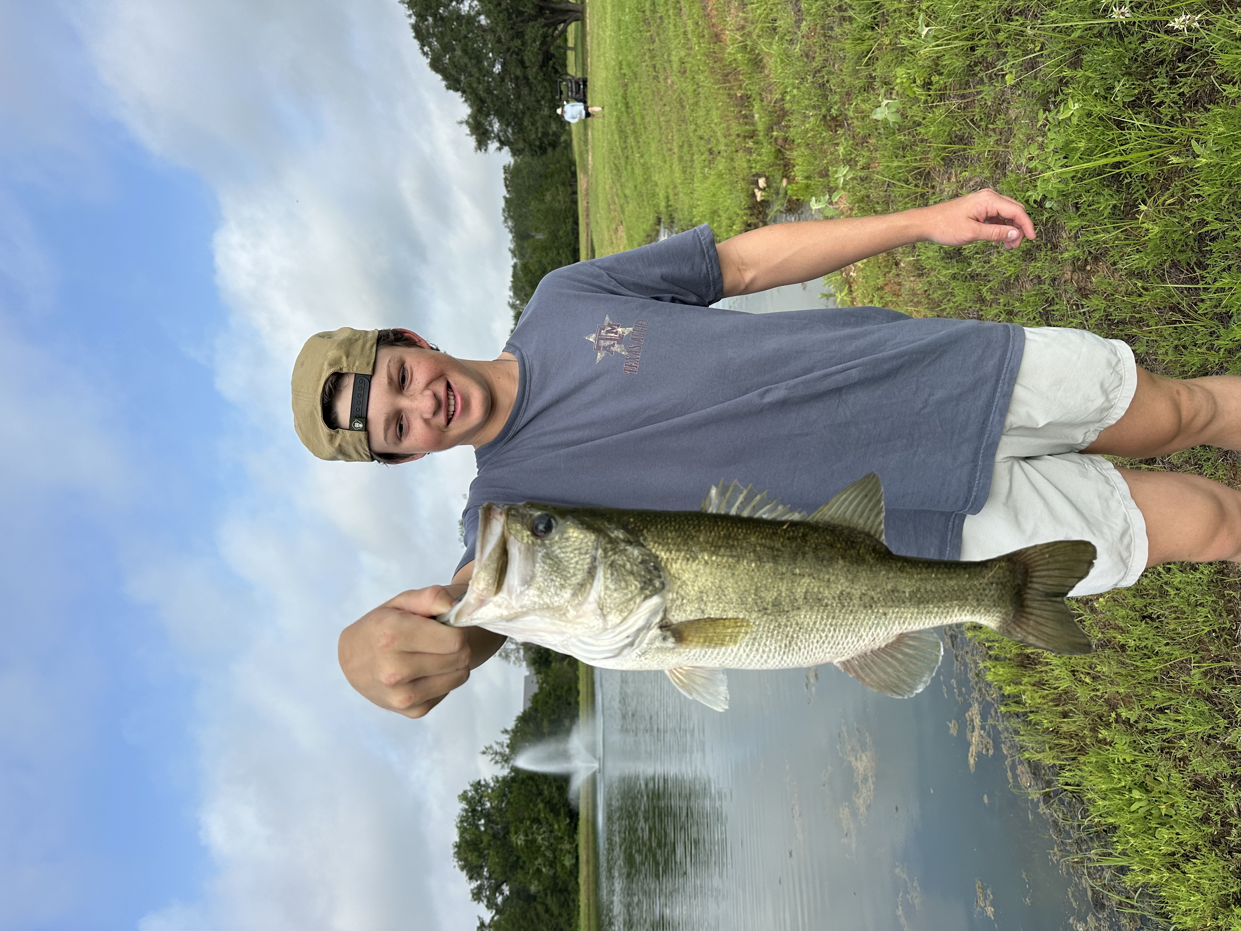 Angler holding a largemouth bass caught on a Chuck's Bass Candy handcrafted soft plastic lure — Pondside pig — bagged on a Chuck's original.